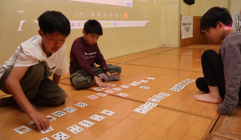 【能登半島地震】世界中とオンラインでつながる!能登の子どもたちが世界150人の子どもと一緒に学ぶプログラミング体験を支援 3 %E3%83%88%E3%83%A9%E3%83%B3%E3%83%97%E3%82%92%E4%B8%A6%E3%81%B9%E3%81%A6%E3%81%84%E3%82%8B%E6%A7%98%E5%AD%90 scaled e1748251143229 1536x896 1