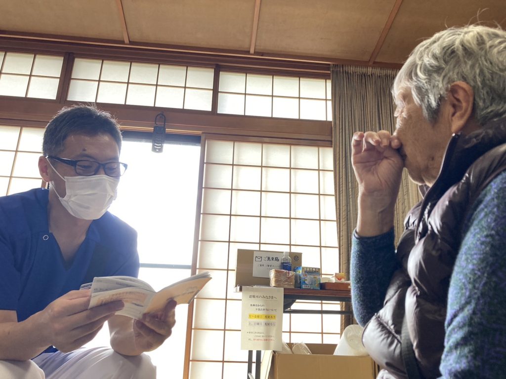 【能登半島地震】地域医療を守ることで支える復興への道 4 薬剤師さんが相談者のおくすり手帳を確認しながら相談に乗っている写真