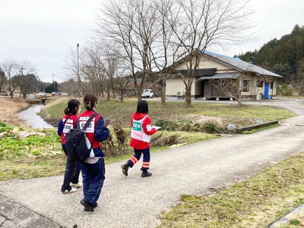 【能登半島地震】地域医療を守ることで支える復興への道 8 空飛ぶ捜索医療団看護師と行政の保健師さんが一緒に戸別訪問に向う写真
